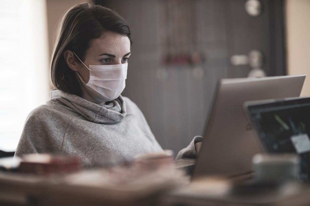 Woman wearing mask working on laptop